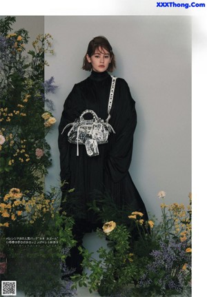 A woman sitting on a chair in front of a bunch of flowers.