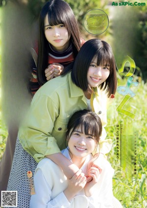 A group of three young women posing for a picture in a field.