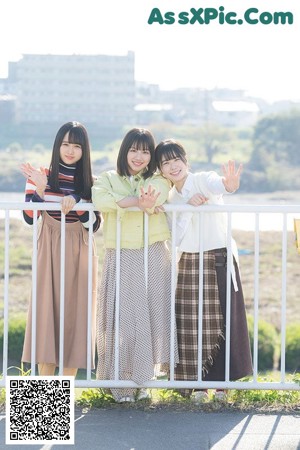 A group of three young women posing for a picture in a field.