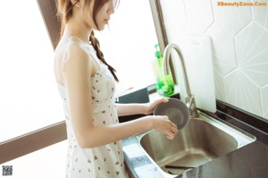 A woman sitting on a kitchen counter eating a bowl of food.