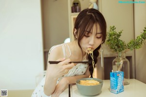 A woman in a white dress holding a bowl of food.