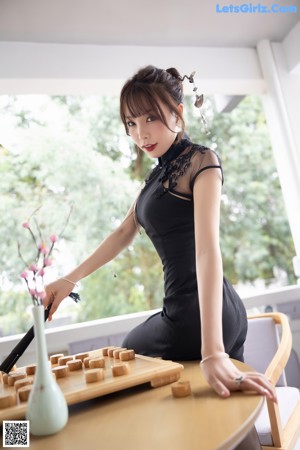 A woman in a black lingerie playing a game of checkers.
