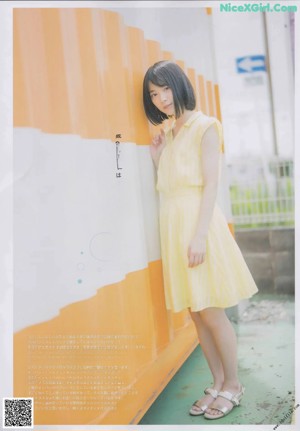 A woman in a yellow dress sitting on the ground.