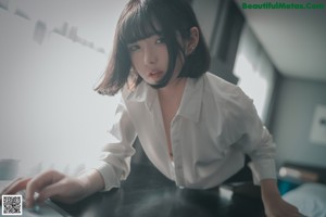 A woman in a white shirt and black stockings sitting on a chair.