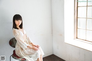 A woman in a white lingerie sitting on a chair.