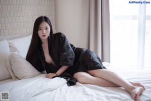 A naked woman laying on a bed with long black hair.