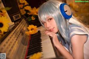 A woman in a white dress sitting on a chair with headphones on.