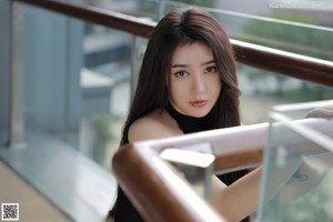 A woman in a black bodysuit sitting on a white couch.