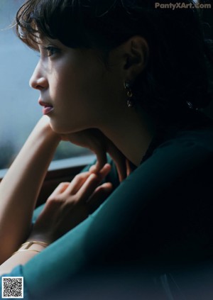 A woman sitting on top of a green chair with her hands on her knees.