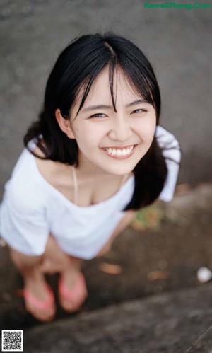 A woman in a white dress sitting on a stone wall.