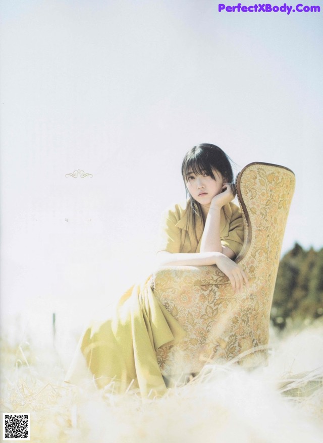 A woman sitting on a chair in a field.