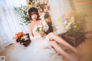 A woman sitting in front of a bunch of flowers.