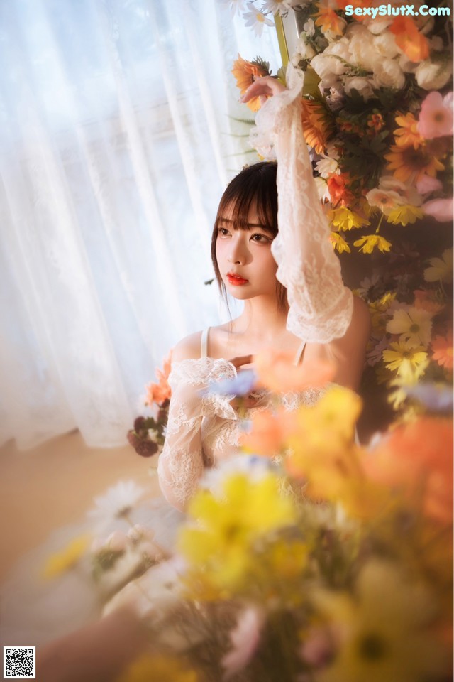 A woman in a white dress holding a bunch of flowers.