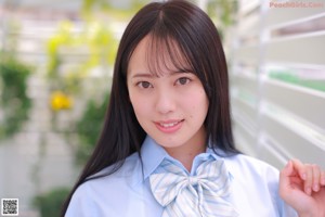 A woman in a blue shirt and plaid skirt posing for a picture.