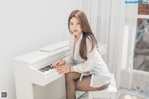 A woman in a white shirt and black stockings sitting on a window sill.