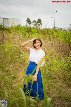 A woman in a blue shirt standing in a field.