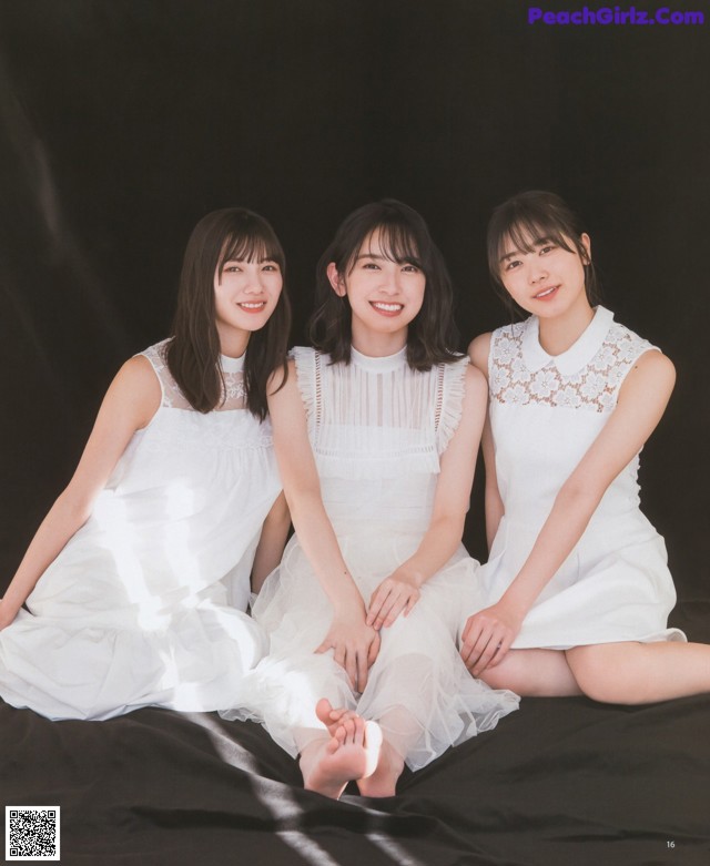 A group of three young women sitting on top of a bed.