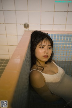 A woman in a white bra looking out a window.