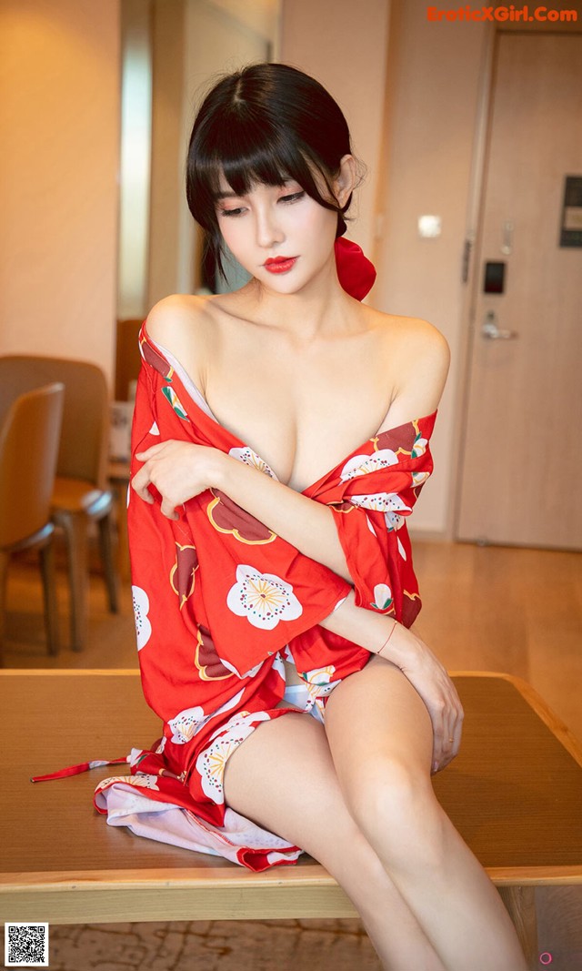 A woman in a red kimono sitting on a table.