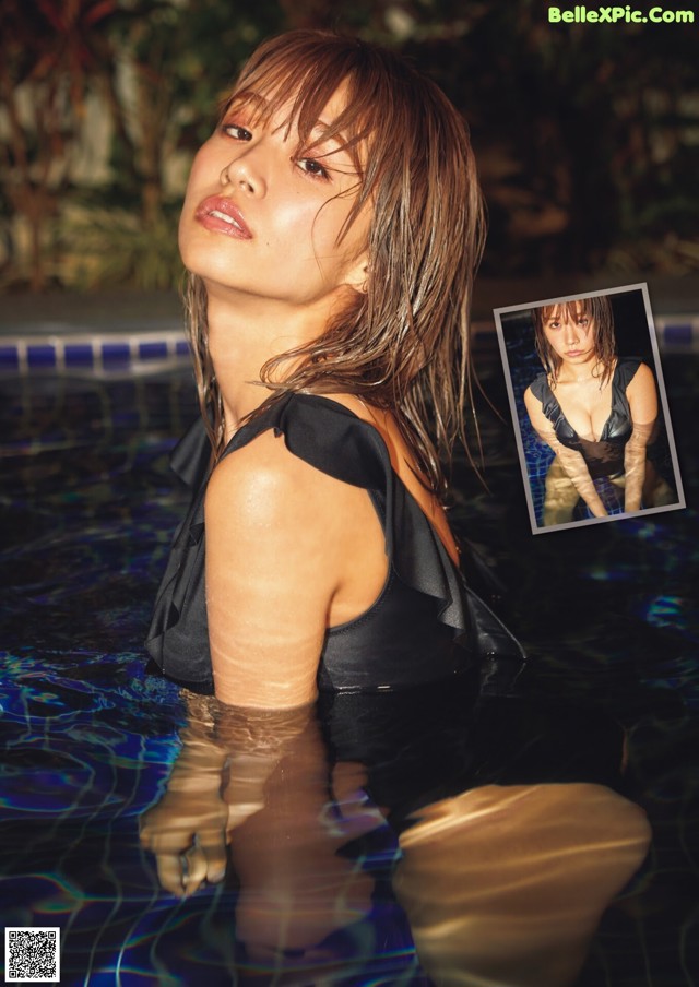 A woman in a black bathing suit standing in a pool.