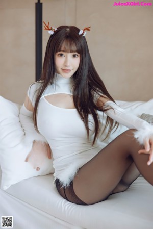 A woman sitting on a white couch wearing black stockings.