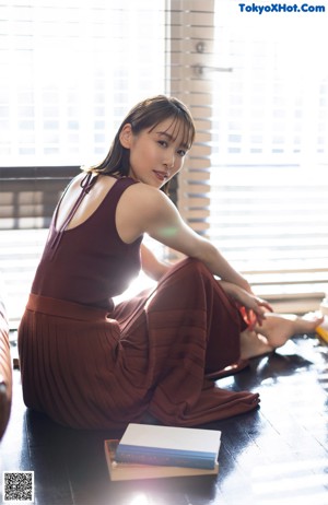 A woman in a red dress is reading a book.