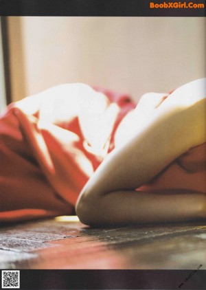 A woman sitting on the ground with her hands on her face.