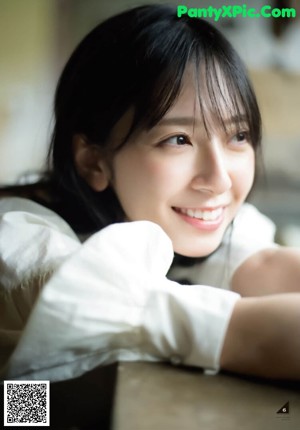 A woman in a white shirt smiles at the camera.