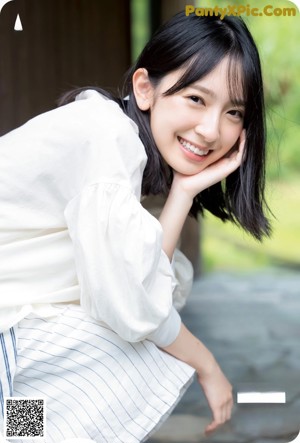 A woman standing in front of a bookshelf wearing a white shirt.