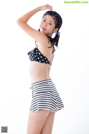 A young girl wearing a black and white polka dot bikini top and striped shorts.