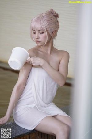 A woman in a pink lingerie sitting on a bed.