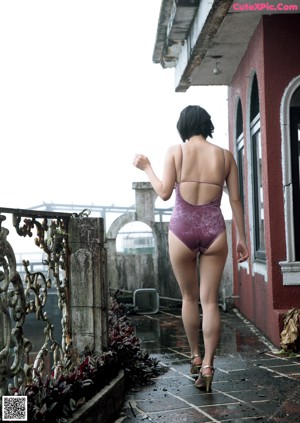 A woman in a purple bathing suit standing in a puddle.