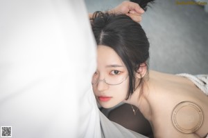 A woman in black stockings and a white shirt is holding a syringe.