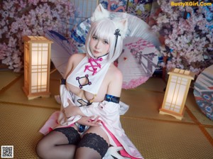 A woman in a cat costume sitting on the floor with an umbrella.