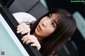 A woman in a white shirt and red tie leaning against a wall.