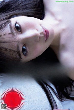 A naked woman laying on a bed with her hands up.