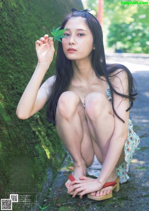 A woman in a white bikini sitting on a tatami mat.