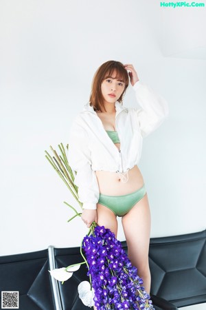 A woman in a white shirt and green panties holding a bouquet of flowers.