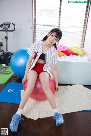 A woman sitting on top of a red ball in a room.