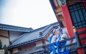 A woman in a blue dress and white fur coat posing for a picture.