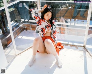 A woman standing in front of a window with her back to the camera.