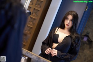A woman in a black lingerie sitting in a bathtub.