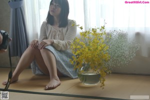 A naked asian woman standing in a shower with her arms crossed.