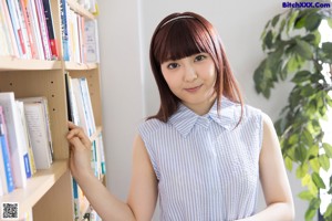 A woman in a pink bikini standing in front of a bookshelf.