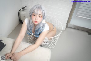 A woman with blue hair sitting on a white couch.