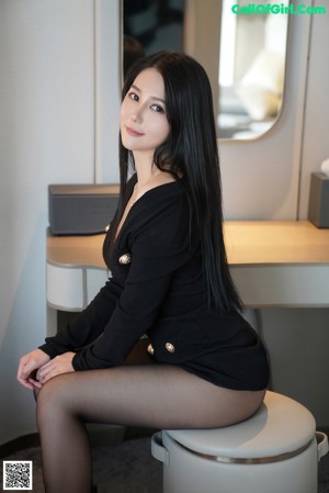 A woman in a black dress and stockings posing in front of a television.