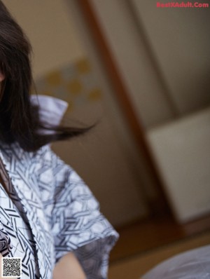 A woman in a black and white kimono standing in a kitchen.