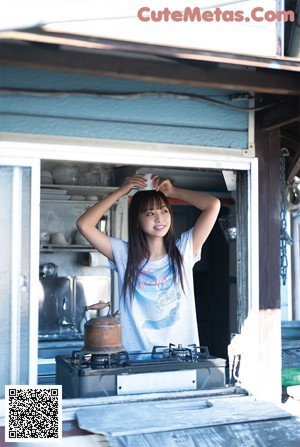 A woman standing in the doorway of a blue house.