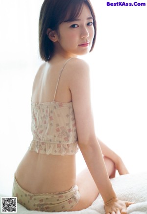 A woman in a white bra and panties sitting on a chair.