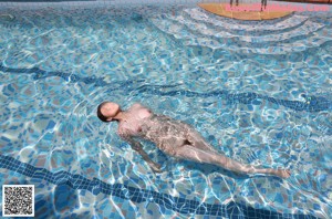 A naked woman standing on the edge of a swimming pool.